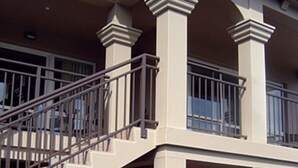 Un bâtiment à deux étages doté d’un balcon, d’un escalier et d’un espace extérieur abrité avec des sièges.