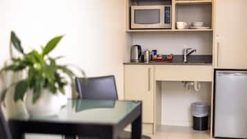 A compact kitchen with a microwave, kettle, and coffee maker on the countertop.