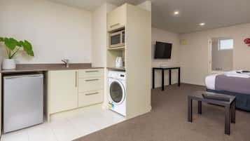 Quarto de hotel compacto com cozinha compacta, máquina de lavar roupa, cama e televisão.