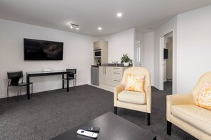 Een moderne woonkamer met een flatscreen televisie, een eettafel met stoelen, een bank en een salontafel.