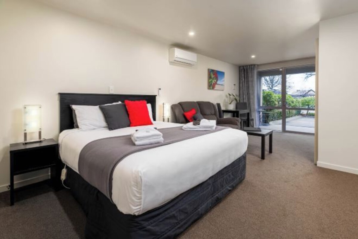 Une chambre d’hôtel avec un grand lit, un bureau, une chaise et une vue sur l’extérieur.