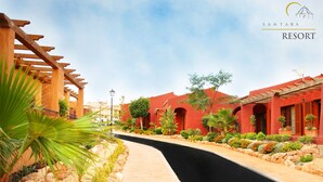 Un sendero que conduce a un edificio rojo con una pérgola a la izquierda.