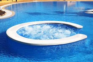 Una piscina techada, una piscina al aire libre, sombrillas