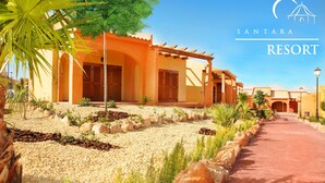 Un resort con un camino que lleva a un edificio con arcos y una pérgola.
