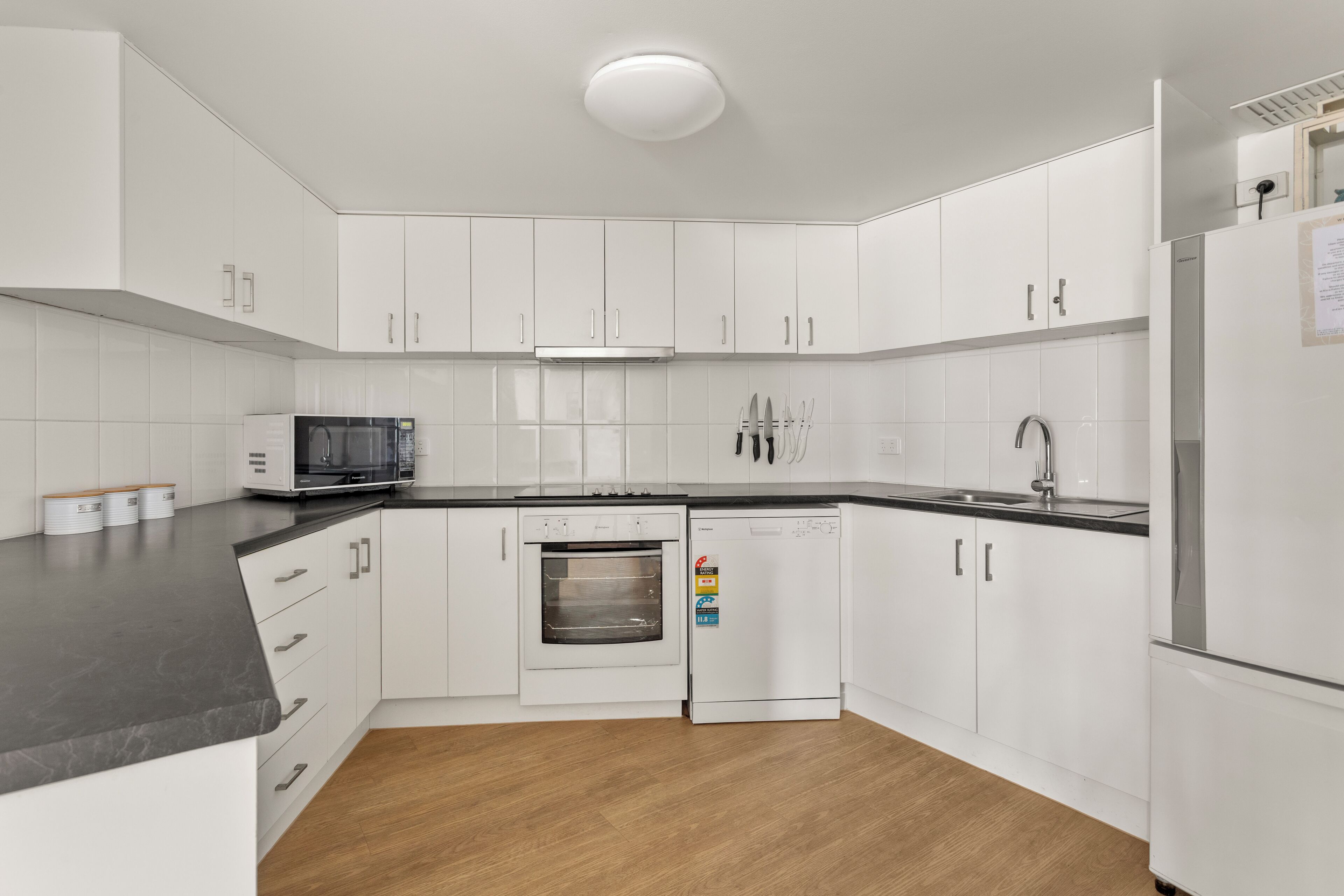 A modern kitchen with white cabinets, a microwave, an oven, and a dishwasher.