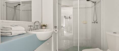 A modern bathroom with a shower, toilet, sink, and a mirror.
