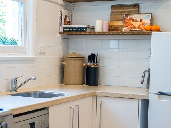 A kitchen with a double sink, a slow cooker, a knife block, and a refrigerator. - Whispering Pines Cottages (Wentworth Falls)