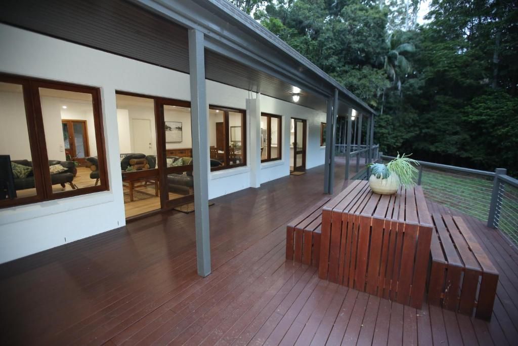 A covered outdoor area with a wooden deck, benches, and a potted plant.