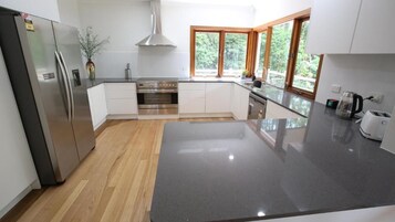 A modern kitchen with a stainless steel refrigerator, built-in oven, and a large granite countertop.