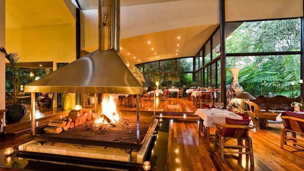 A restaurant with a wood-fired grill, large windows, and a view of the outdoors. - Pethers Rainforest Retreat (Tamborine Mountain)