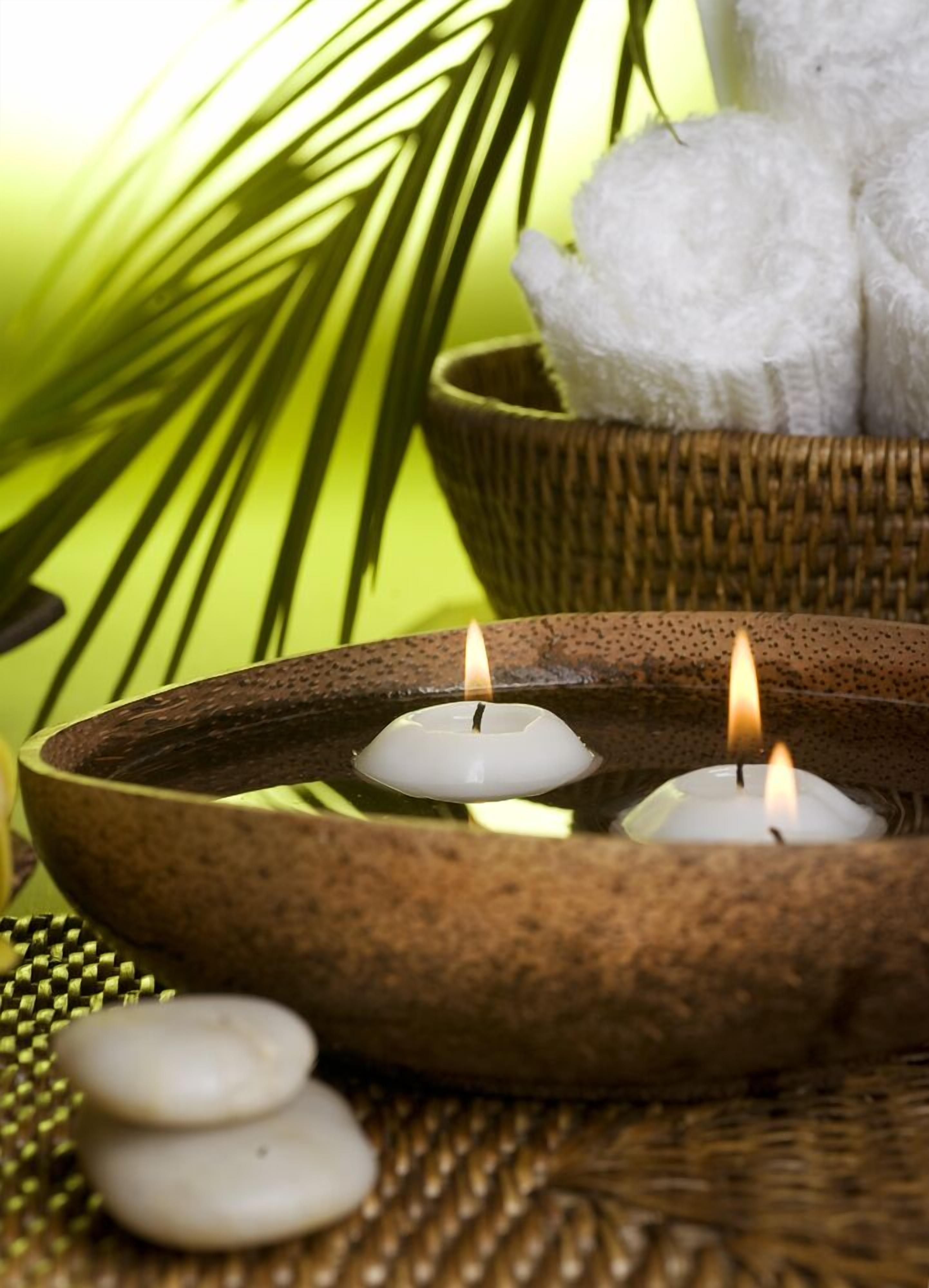 A candlelit setting with a bowl, candles, and spa towels.
