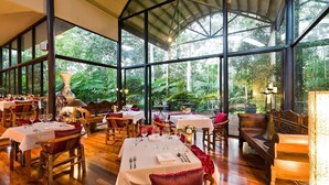 A restaurant with tables set for dining, large windows, and a view of greenery. - Pethers Rainforest Retreat (Tamborine Mountain)