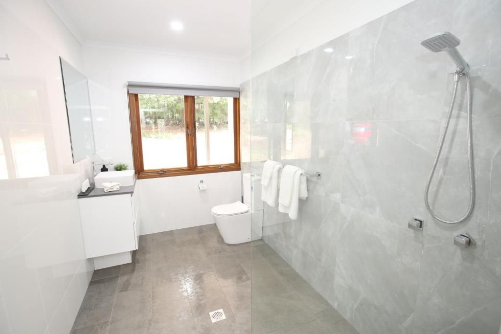 A modern bathroom with a shower, toilet, and vanity.