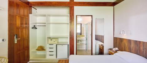 Ein Schlafzimmer mit Bett, Kleiderschrank, kleinem Schreibtisch, Spiegel und Dusche.