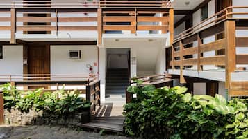 Un immeuble à plusieurs étages doté d’une cour pavée de pierres, de balcons en bois et d’un escalier menant à l’entrée.