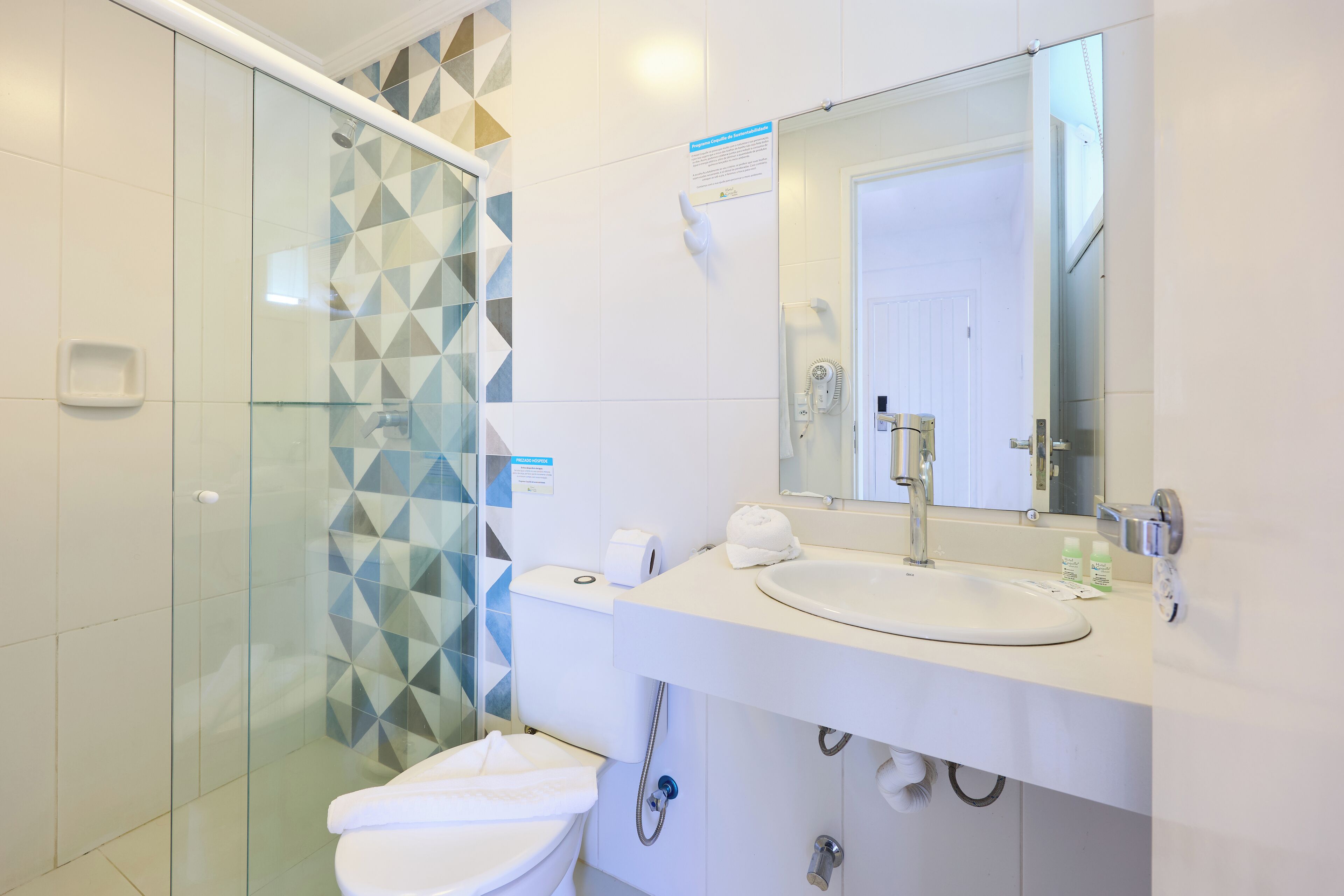 A modern bathroom with a glass shower enclosure, a white sink with a mirror above it, and a toilet.