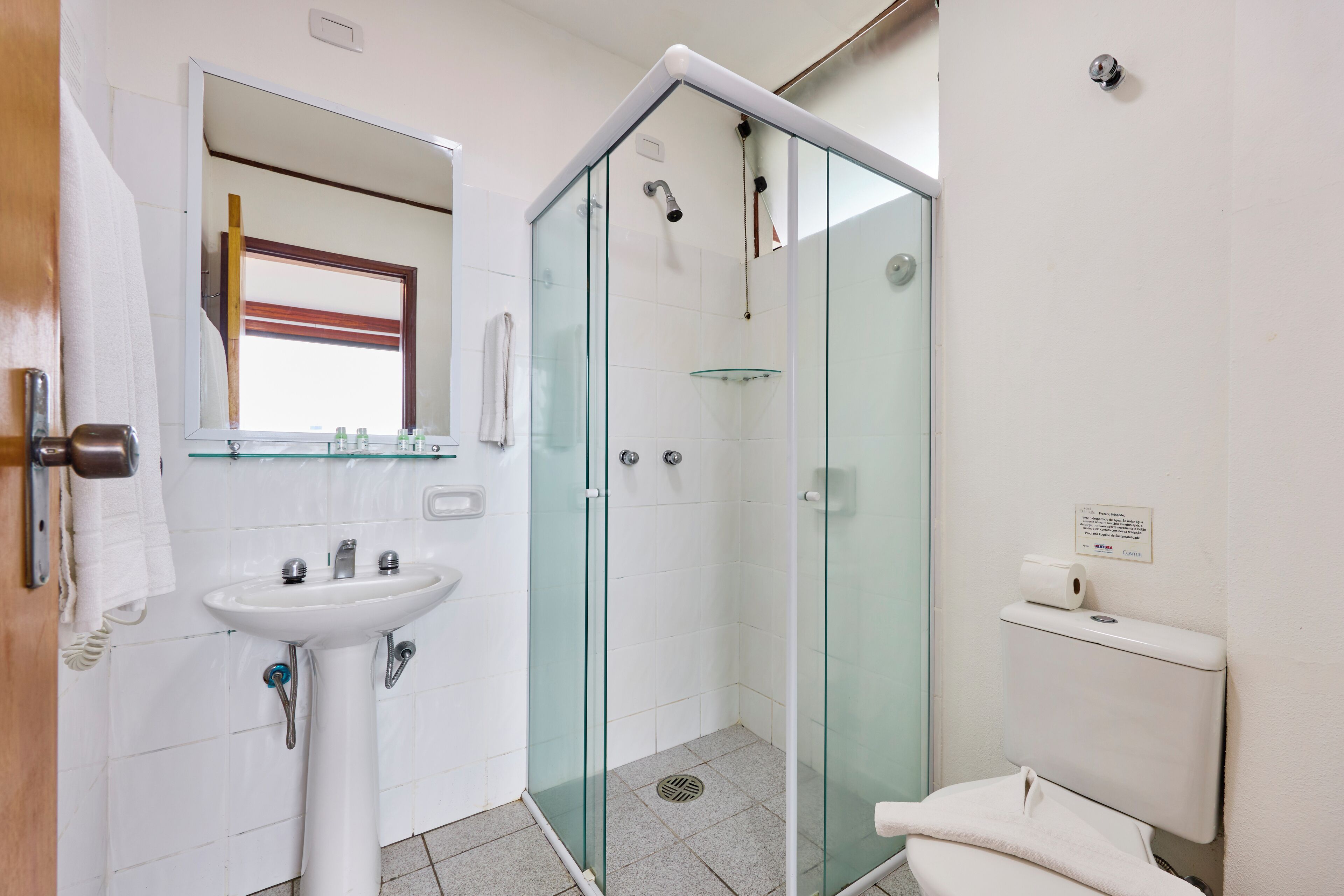 A bathroom with a glass-enclosed shower, a sink with a mirror, and a toilet.