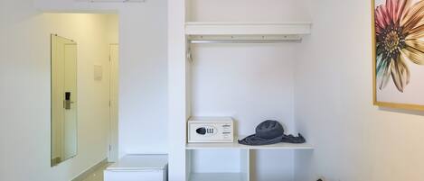 A hotel room with a bed, a small desk, a microwave, a trash bin, and a wall-mounted air conditioner.