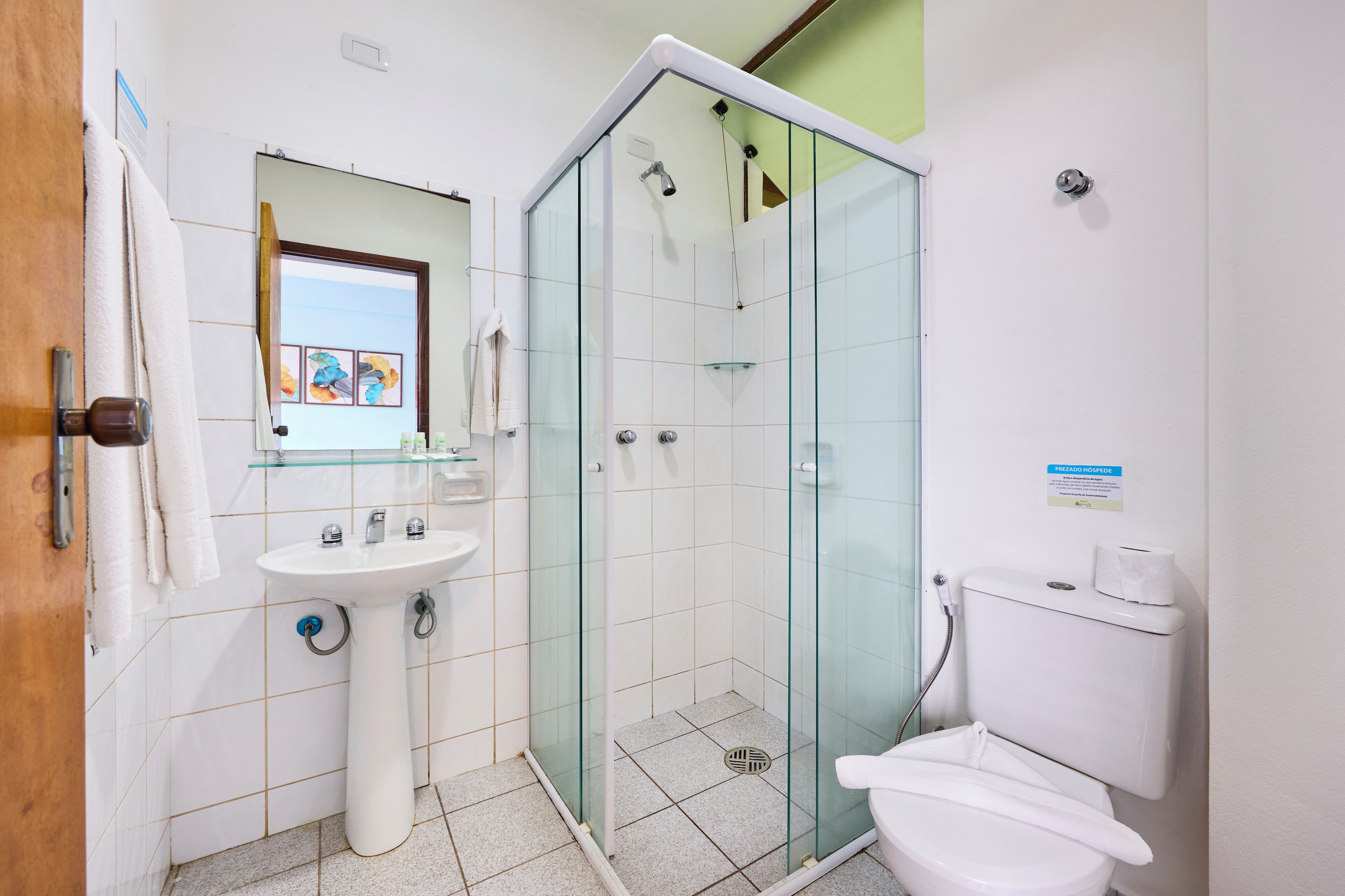A bathroom with a glass-enclosed shower, a sink, and a toilet.