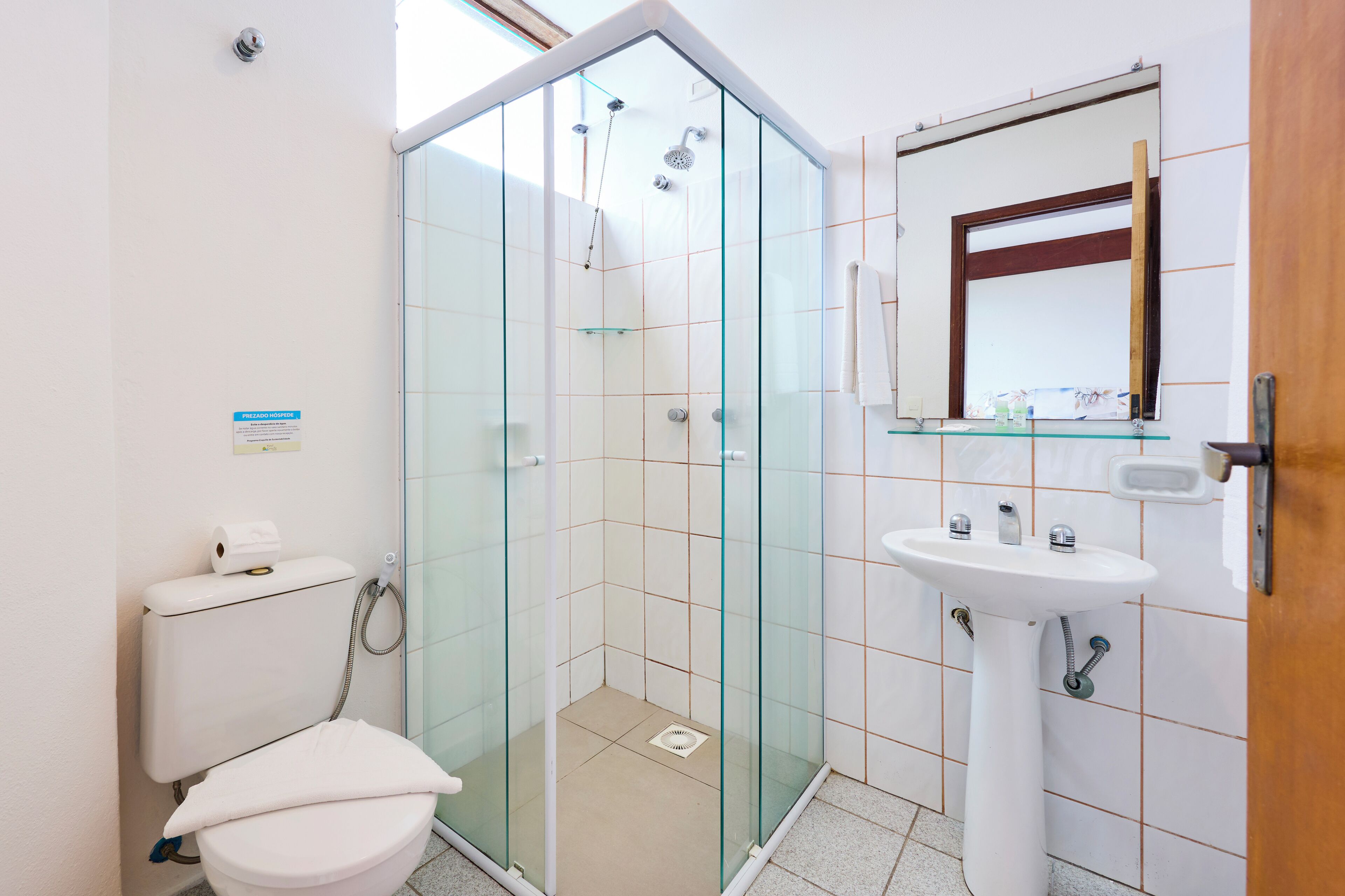 A modern bathroom with a glass-enclosed shower, a toilet, and a sink with a mirror above it.