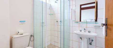 A modern bathroom with a glass-enclosed shower, a toilet, and a sink with a mirror above it.