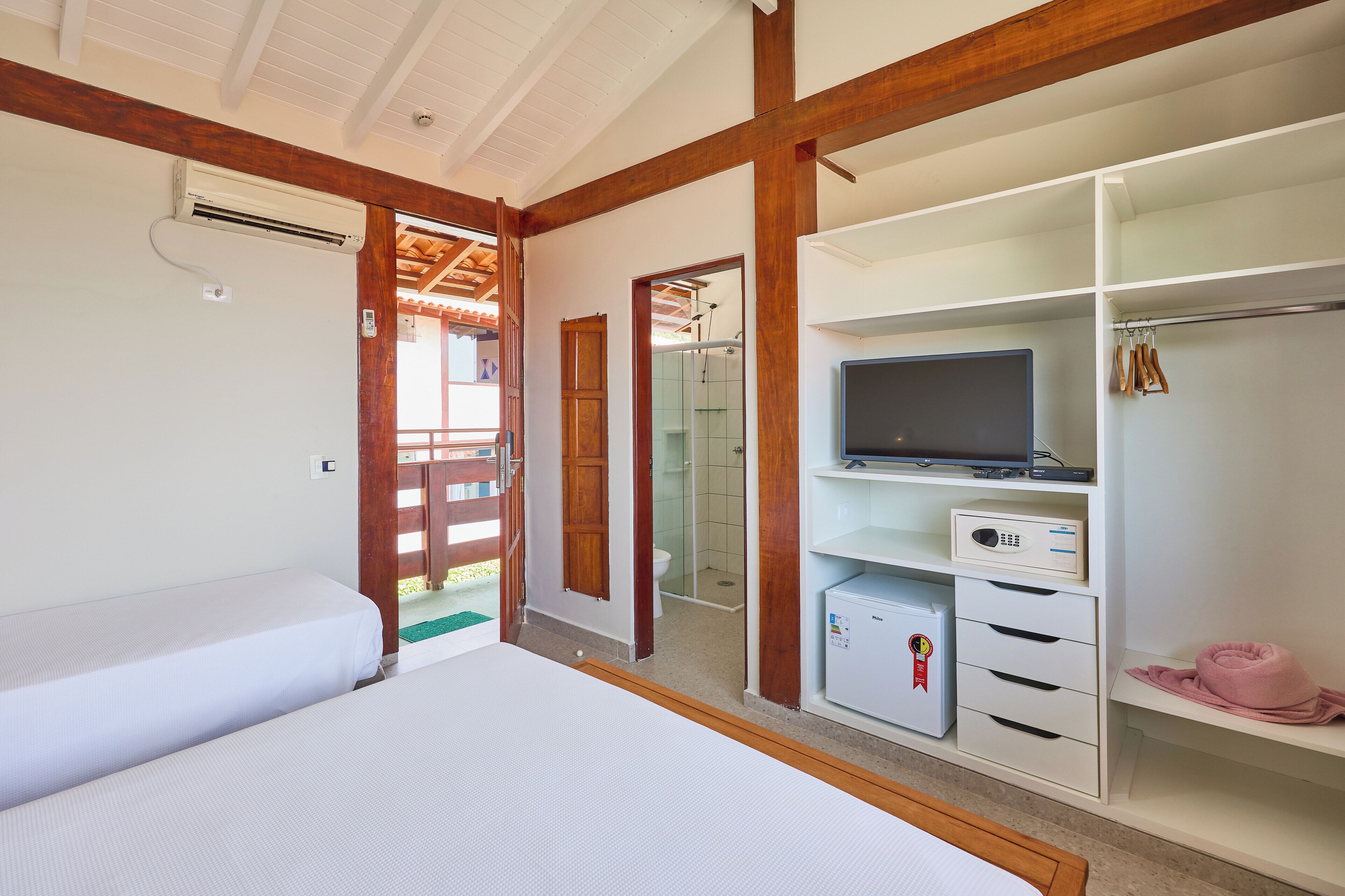 Un dormitorio con cama, televisión, armario y un refrigerador pequeño.