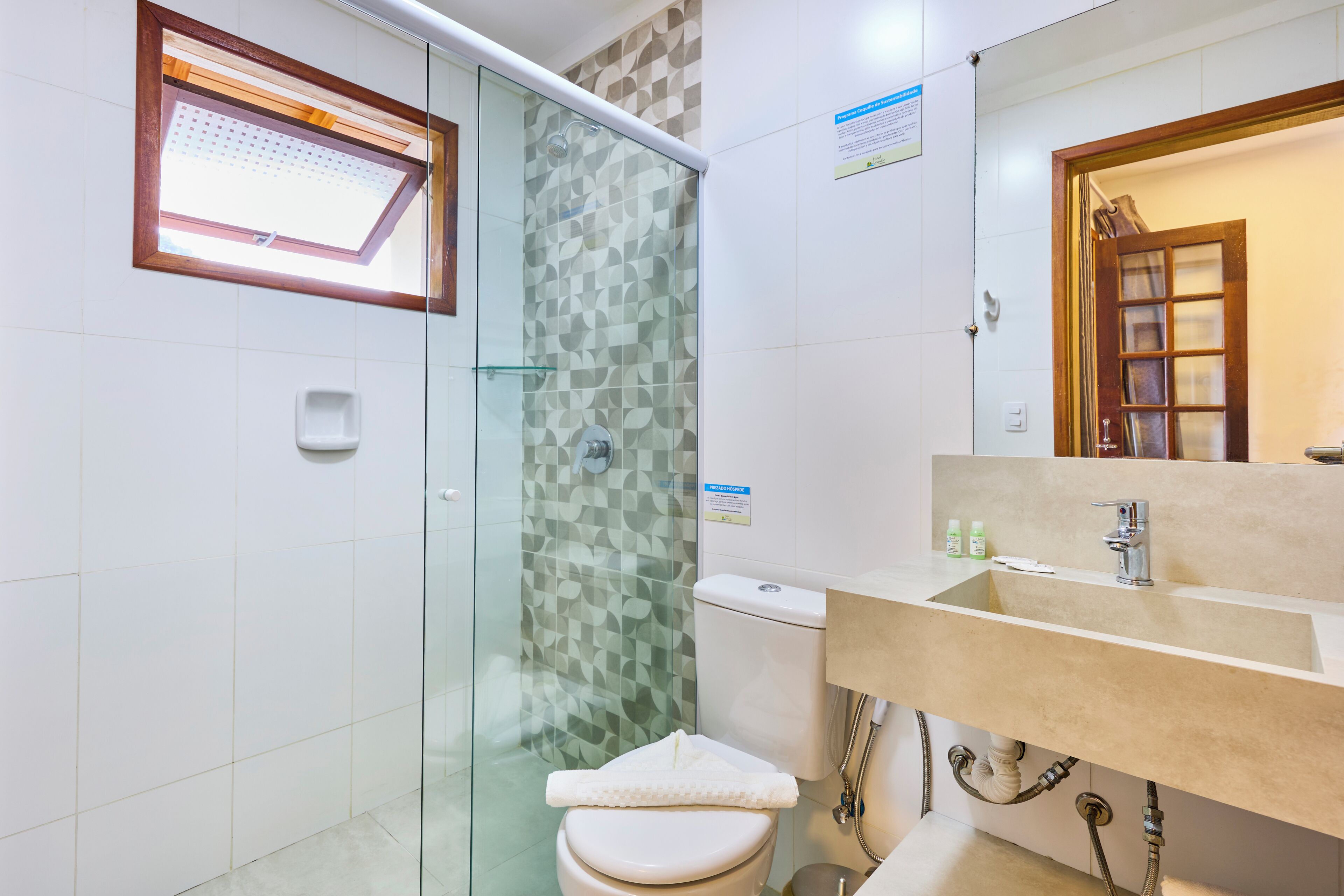 Un baño moderno con ducha de vidrio, inodoro y lavamanos con espejo.