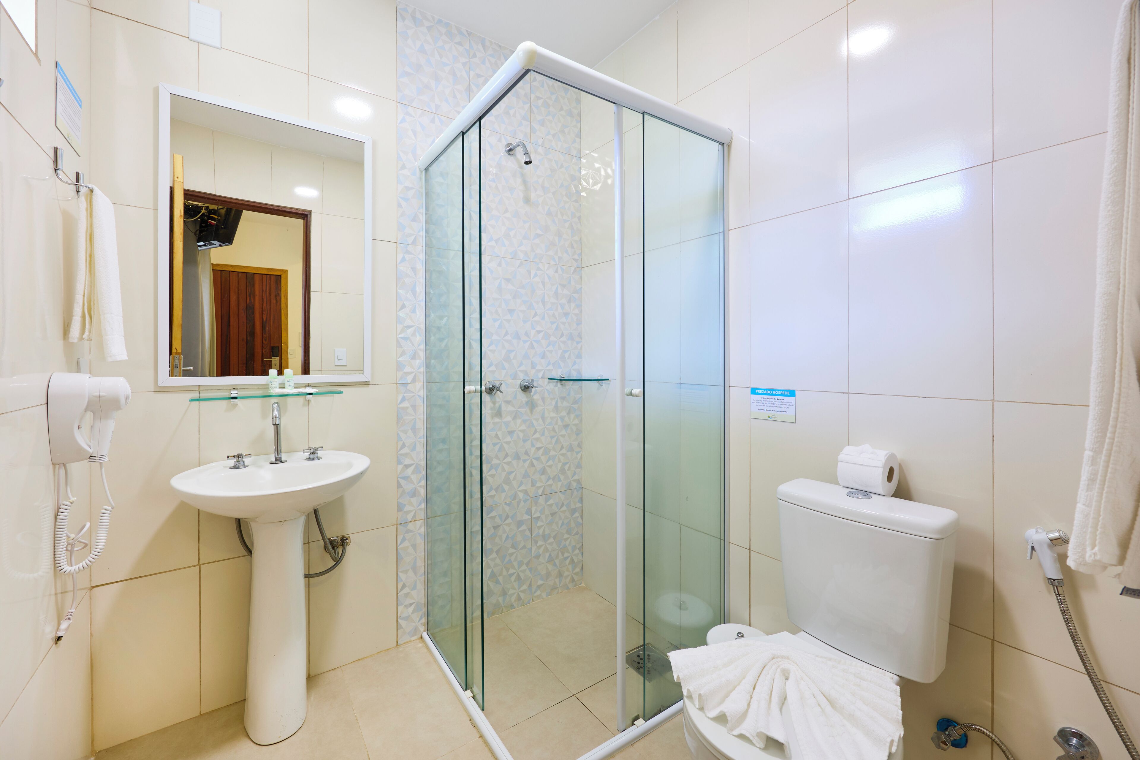 Un baño con ducha de vidrio, lavamanos blanco y un inodoro.