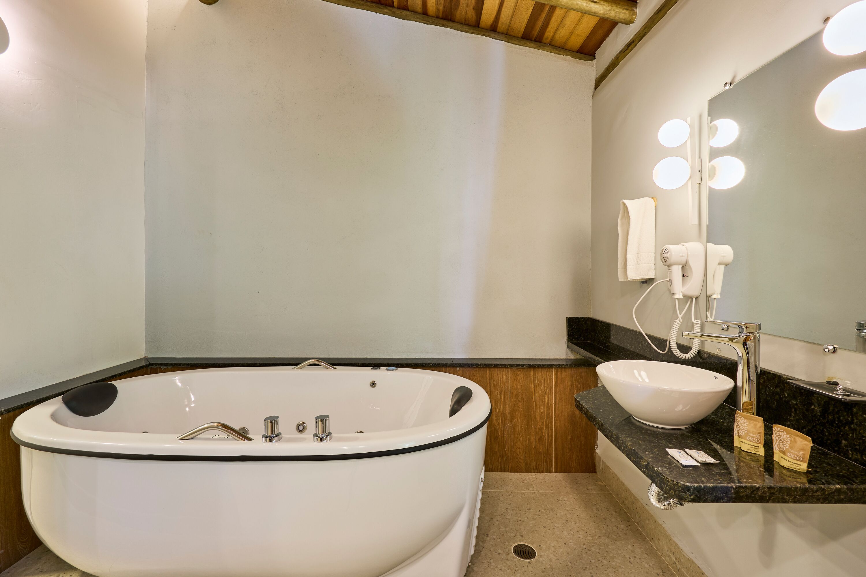 Un baño moderno con una bañera independiente, un tocador con lavamanos y un espejo con iluminación.