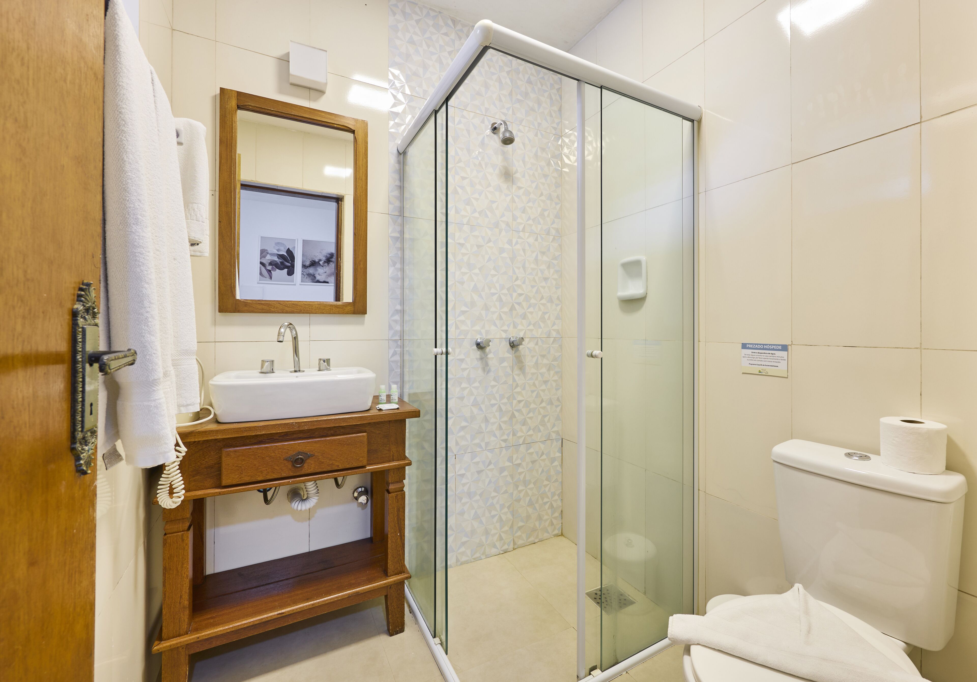 A bathroom with a wooden vanity, a glass shower enclosure, and a toilet.