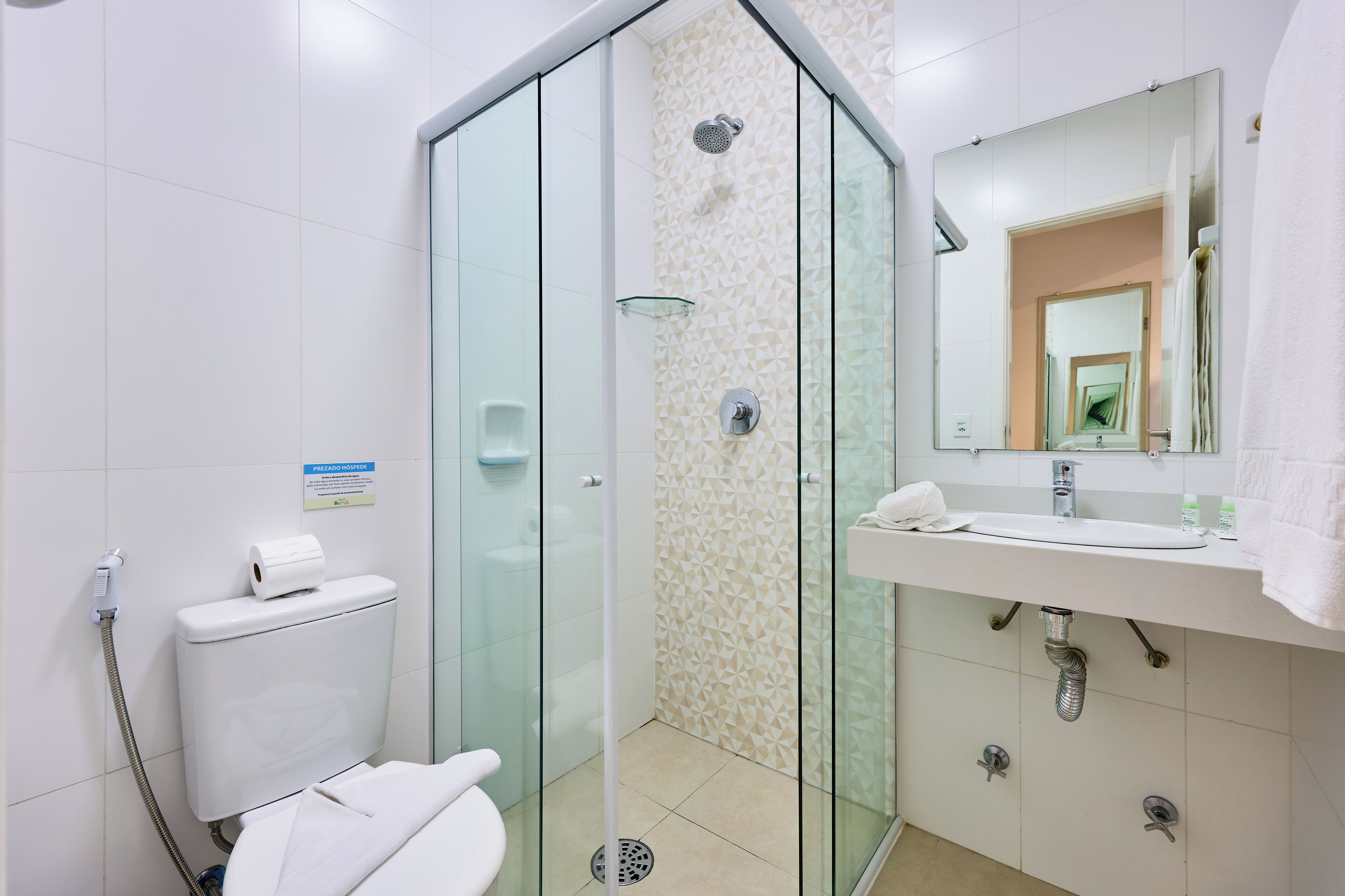 A modern bathroom with a glass-enclosed shower, a toilet, and a sink with a mirror above it.