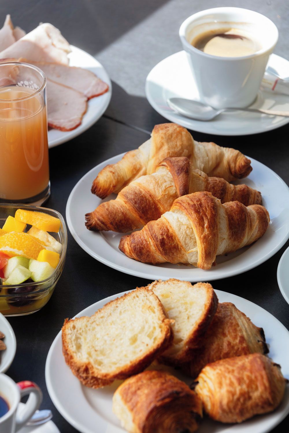 A breakfast setting with croissants, orange juice, and coffee.