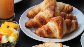 Un desayuno con croissants, zumo de naranja y café.
