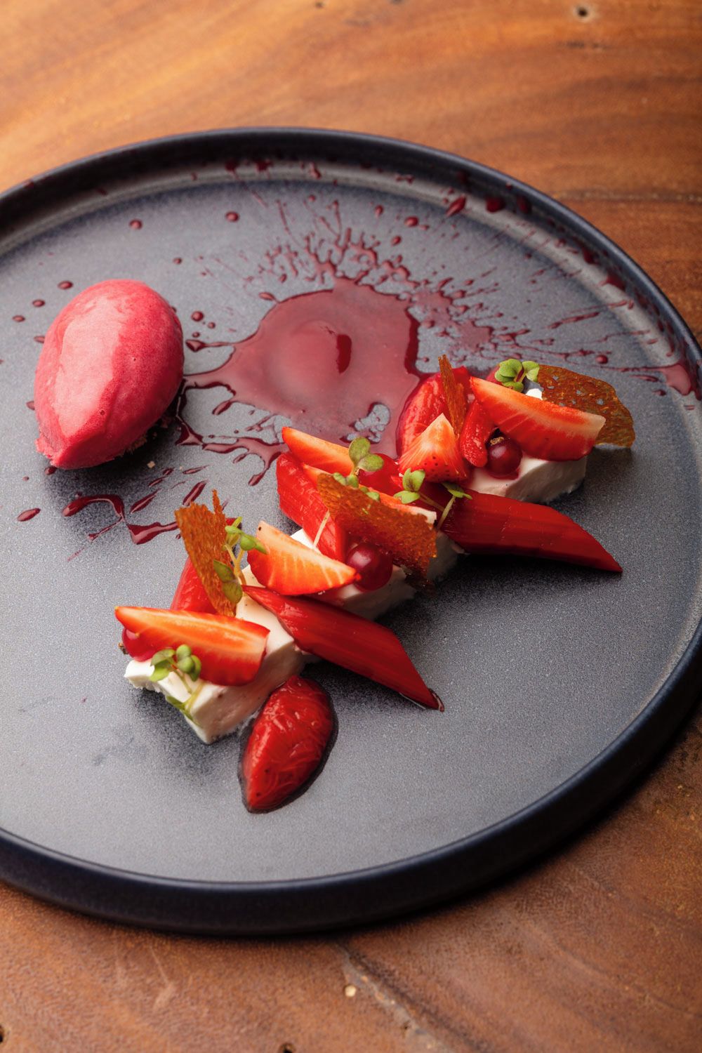 Un piattino con gelato, fragole e salsa.