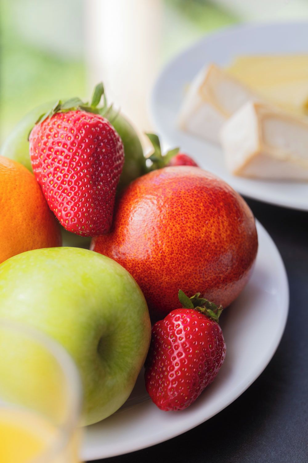 Een bord met aardbeien, appels en kaas.