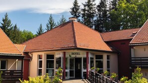 Hotelli, jossa on punatiilikatolla varustettu rakennus, keskeinen sisäänkäynti ja oviin johtava käytävä.