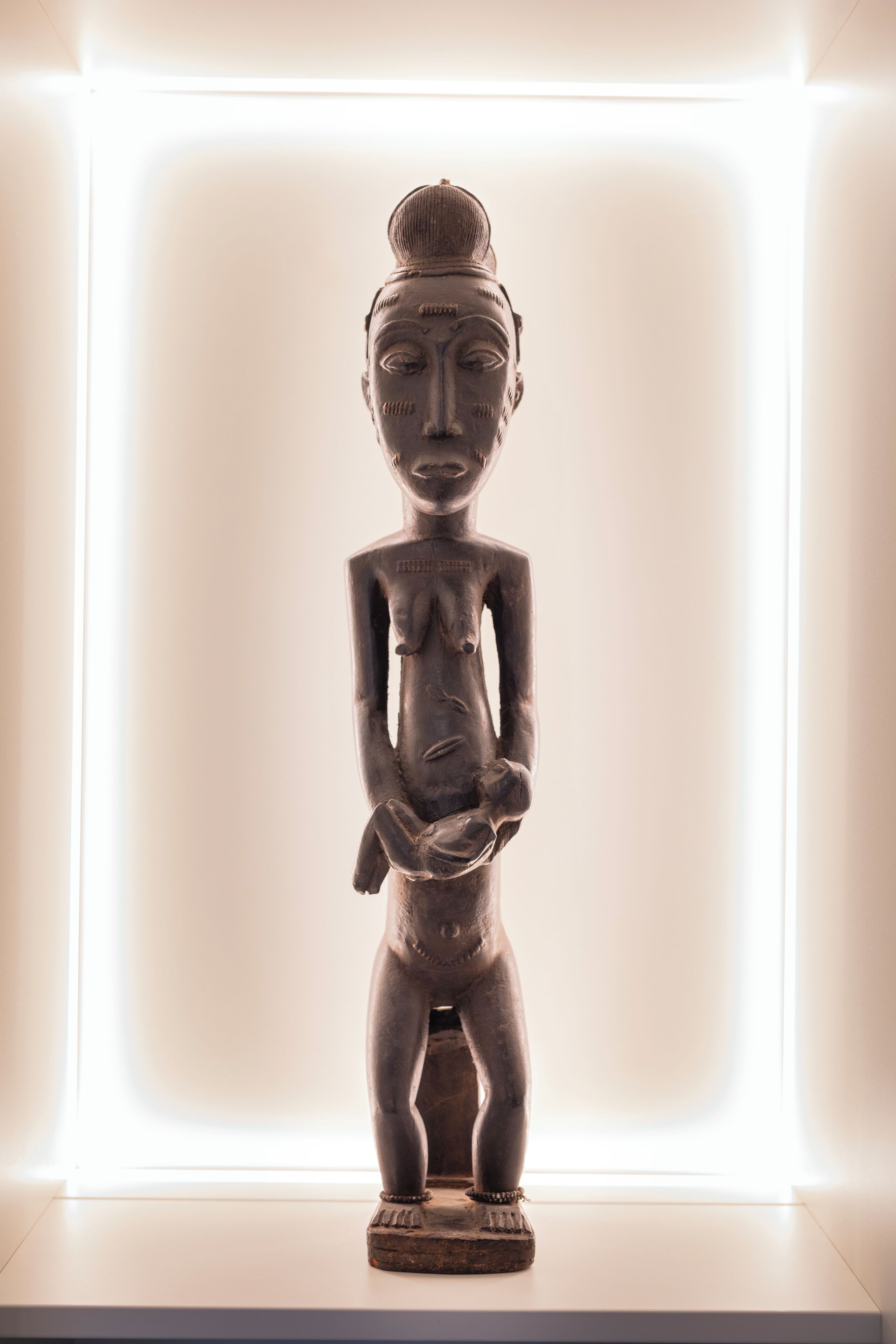 Eine Holzstatue in einem gut beleuchteten Raum mit schlichtem Hintergrund.