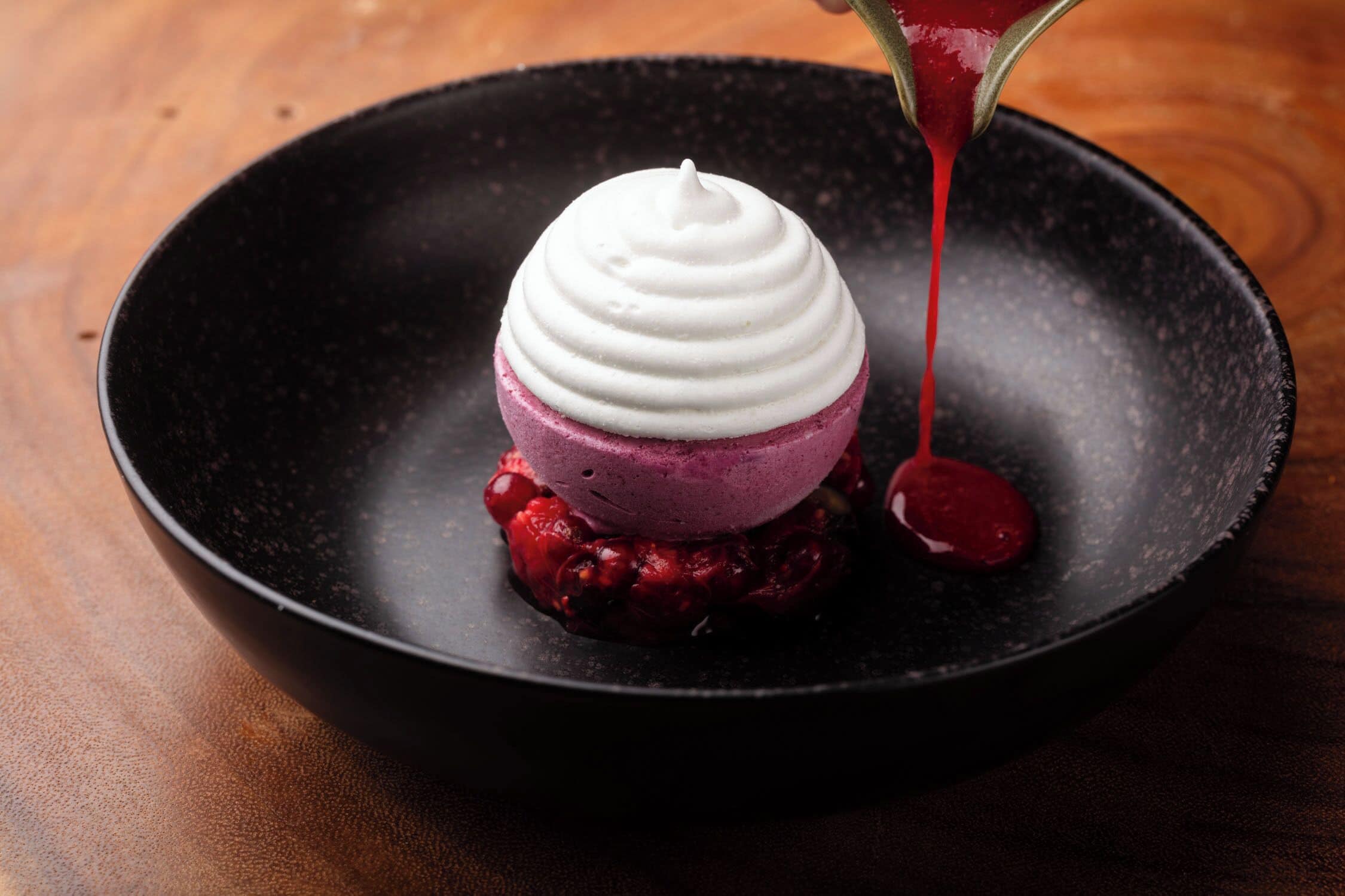 Ein Dessert mit mehrschichtiger Struktur in einer schwarzen Schüssel.