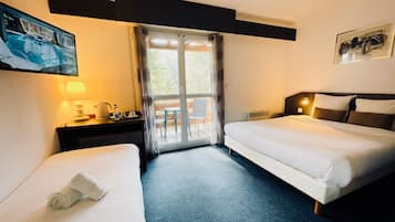 A hotel room with two beds, a desk with a lamp, a television, and a window with curtains.