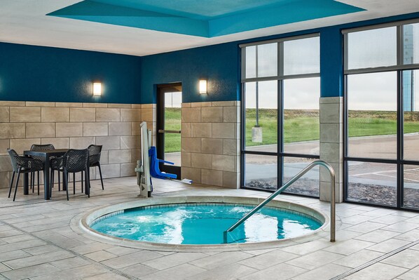 An indoor swimming pool with a seating area and a view of the outdoors.