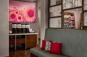 A modern interior with a sofa, a coffee station, and a wall with a sunflower painting.