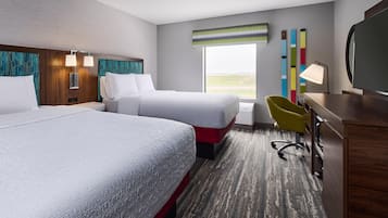 A hotel room with two beds, a desk, a chair, and a large window.