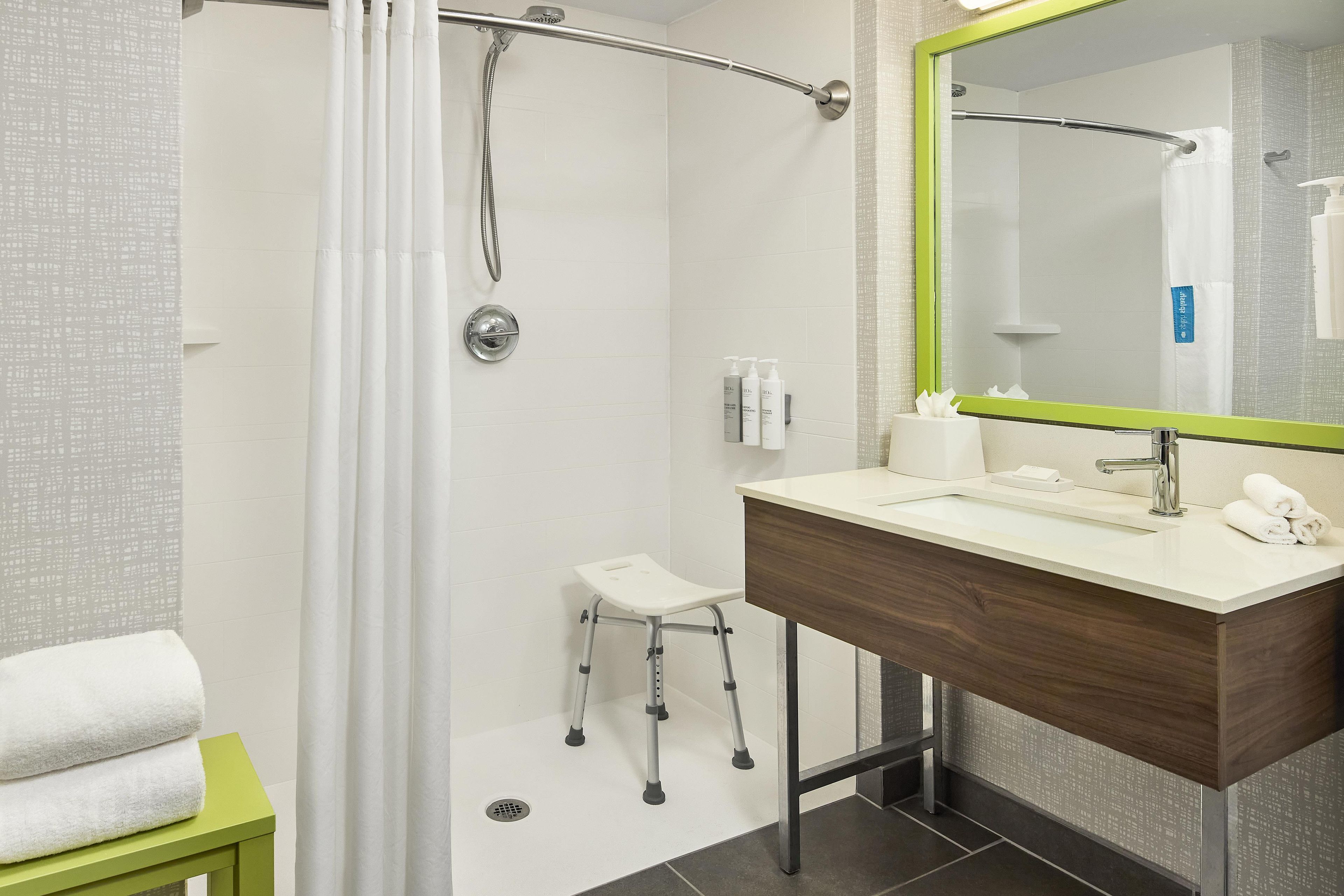 Un baño moderno con ducha, lavamanos y espejo.