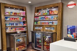 Zona de exhibición de bocadillos y bebidas con estantes llenos de una variedad de productos.