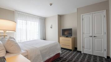 A hotel room with a bed, a TV on a stand, a desk, and a wardrobe.