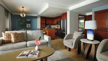 A modern living room with a sofa, armchairs, a coffee table, and a dining area with a kitchen in the background.