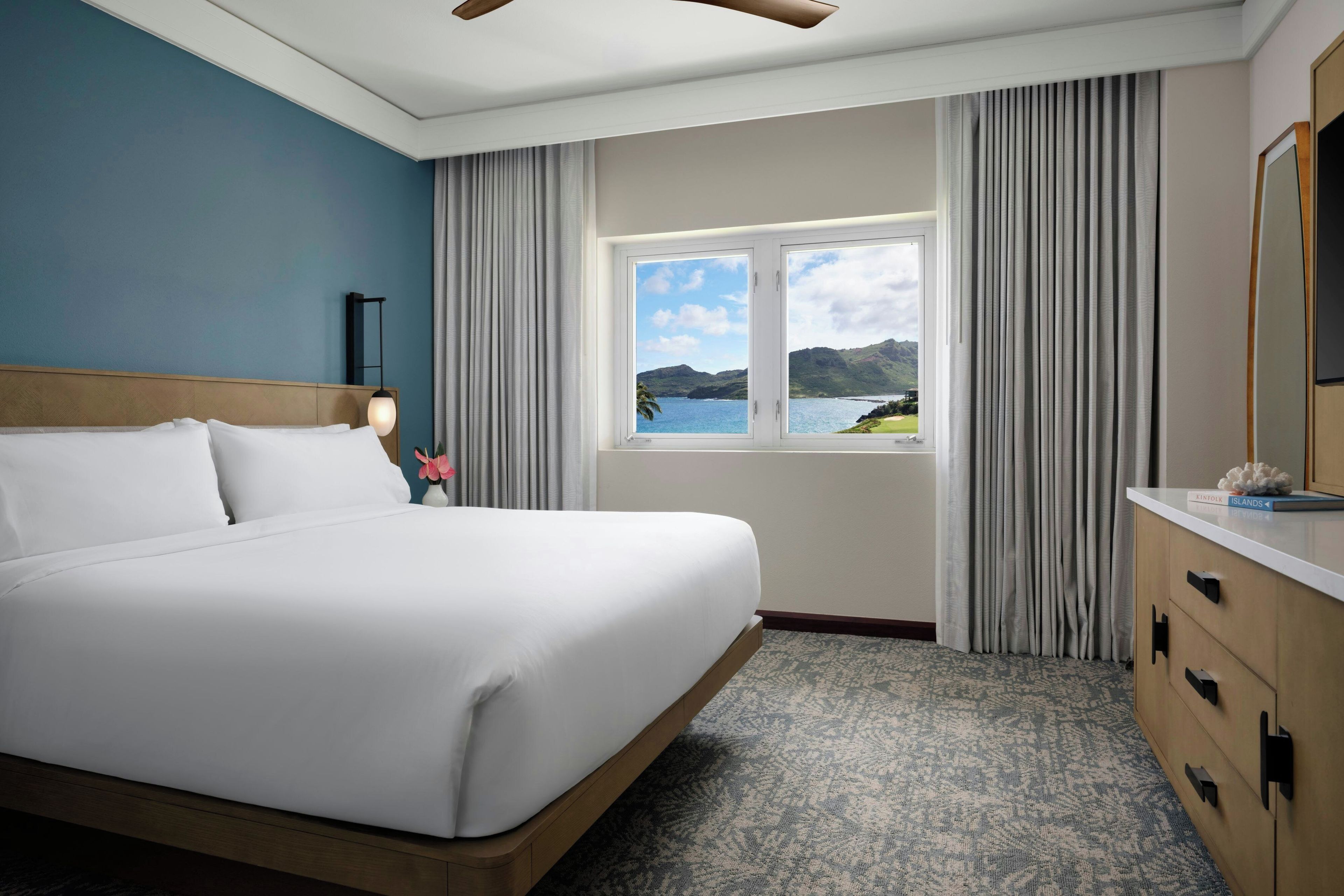A hotel room with a large bed, a view of the sea, and a wooden headboard.