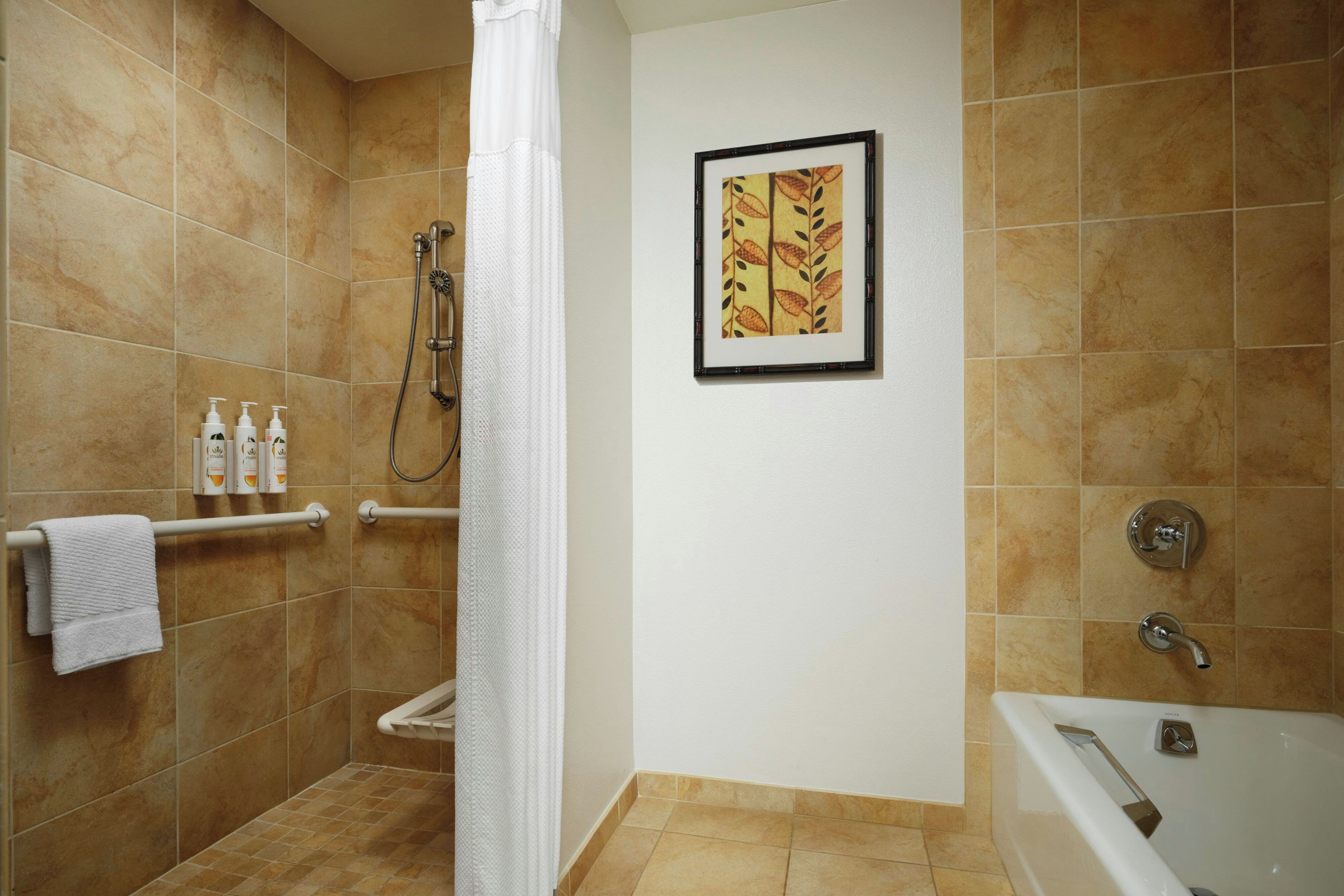 Un baño con ducha, bañera y un perchero con artículos de aseo.