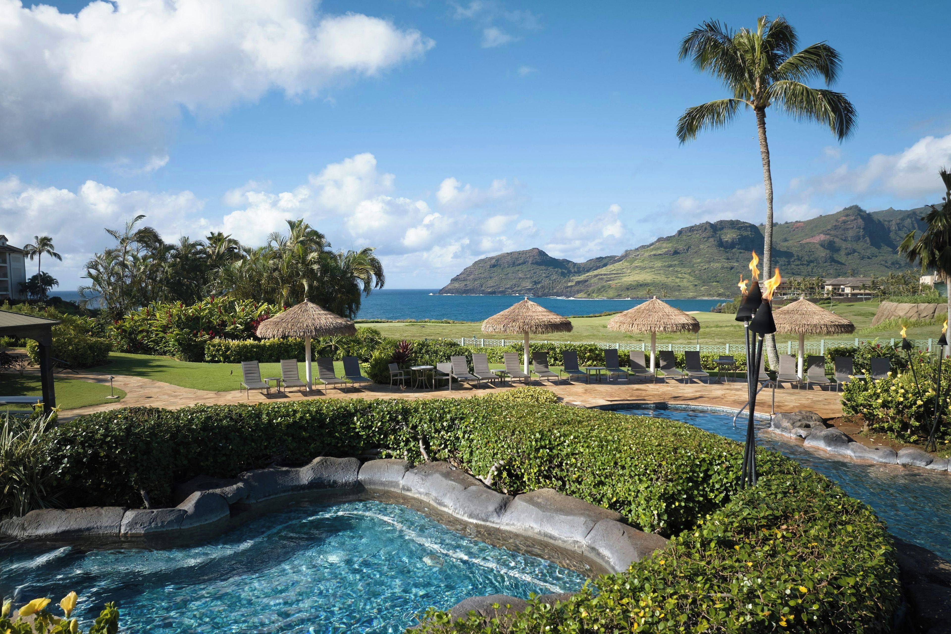 A pool area with a clear view of the ocean and mountains in the background.