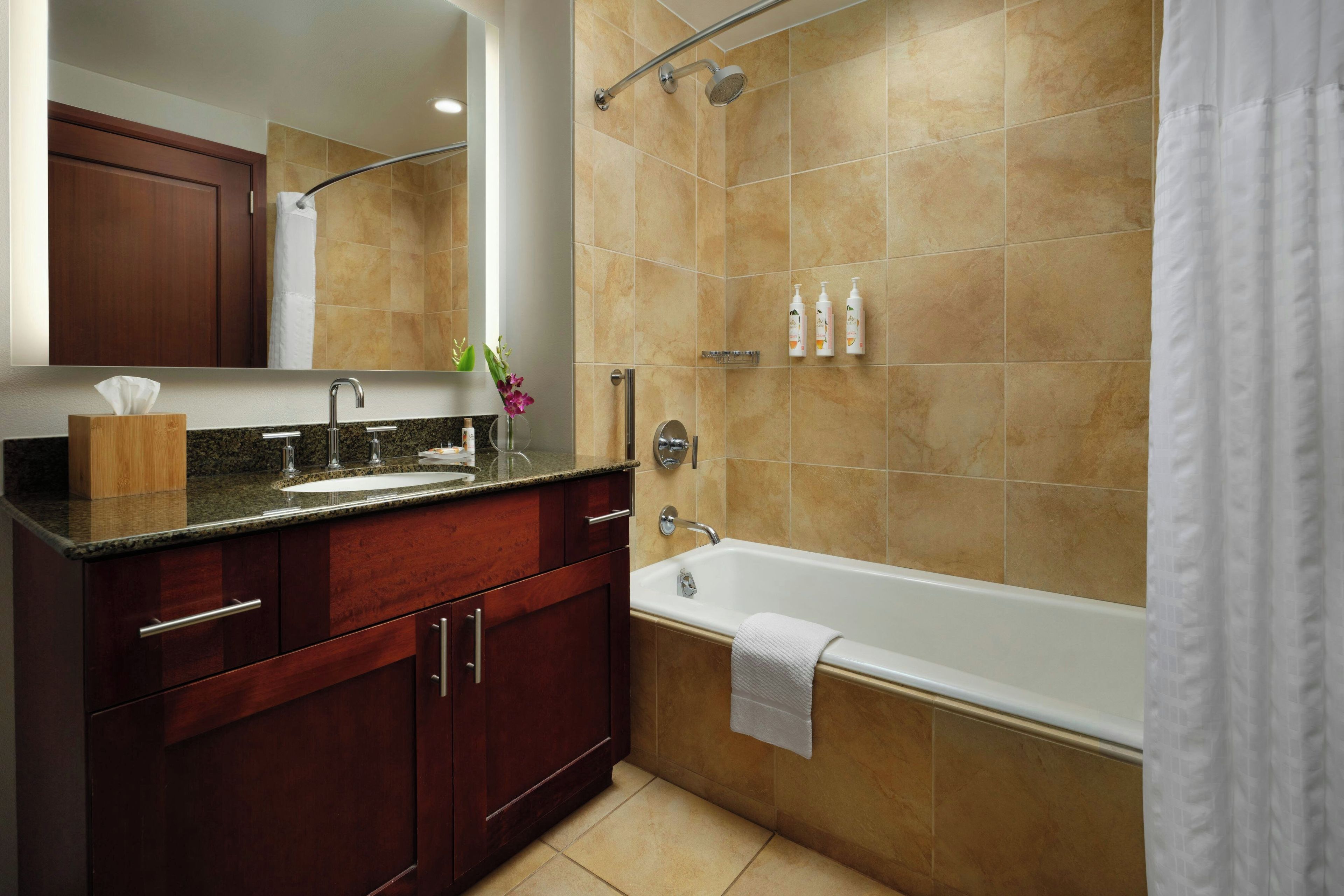 Un baño con tocador, lavamanos, espejo y bañera.